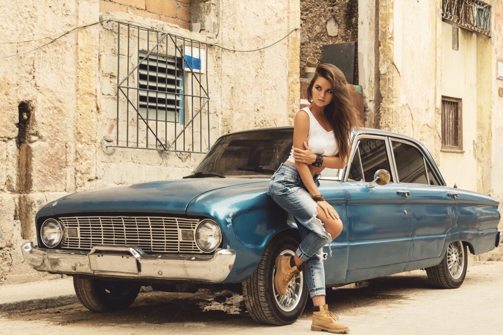 Woman is posing beside old car on the street
